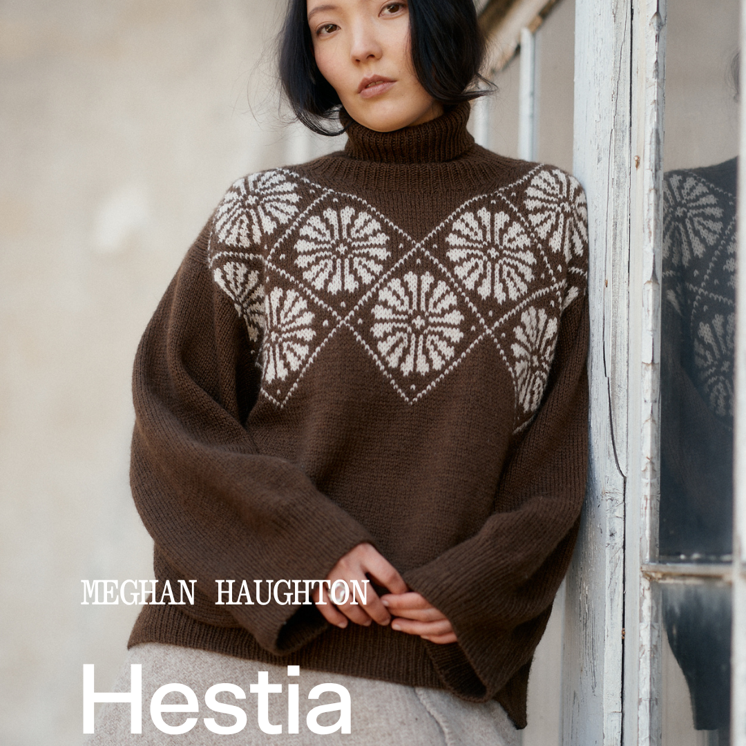 A woman wearing a brown knit sweater with a white geometric Fair Isle yoke pattern and a light gray knit skirt, leaning against a weathered white wooden door. Text overlays read 'MECHAN HAUGHTON', 'Hestia', and 'LAINE'.