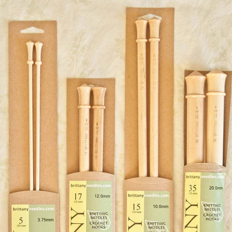 Set of wooden knitting needles with packaging on a beige background
