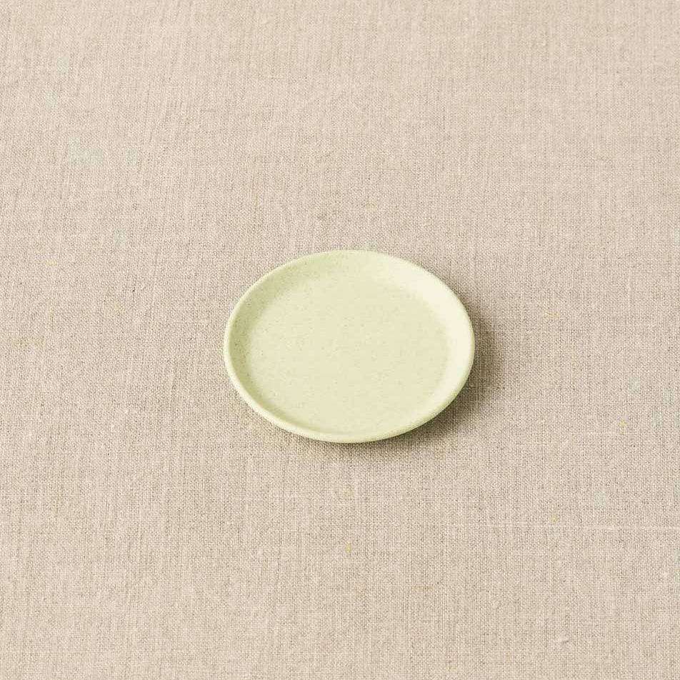 Green ceramic plate on a beige textured surface
