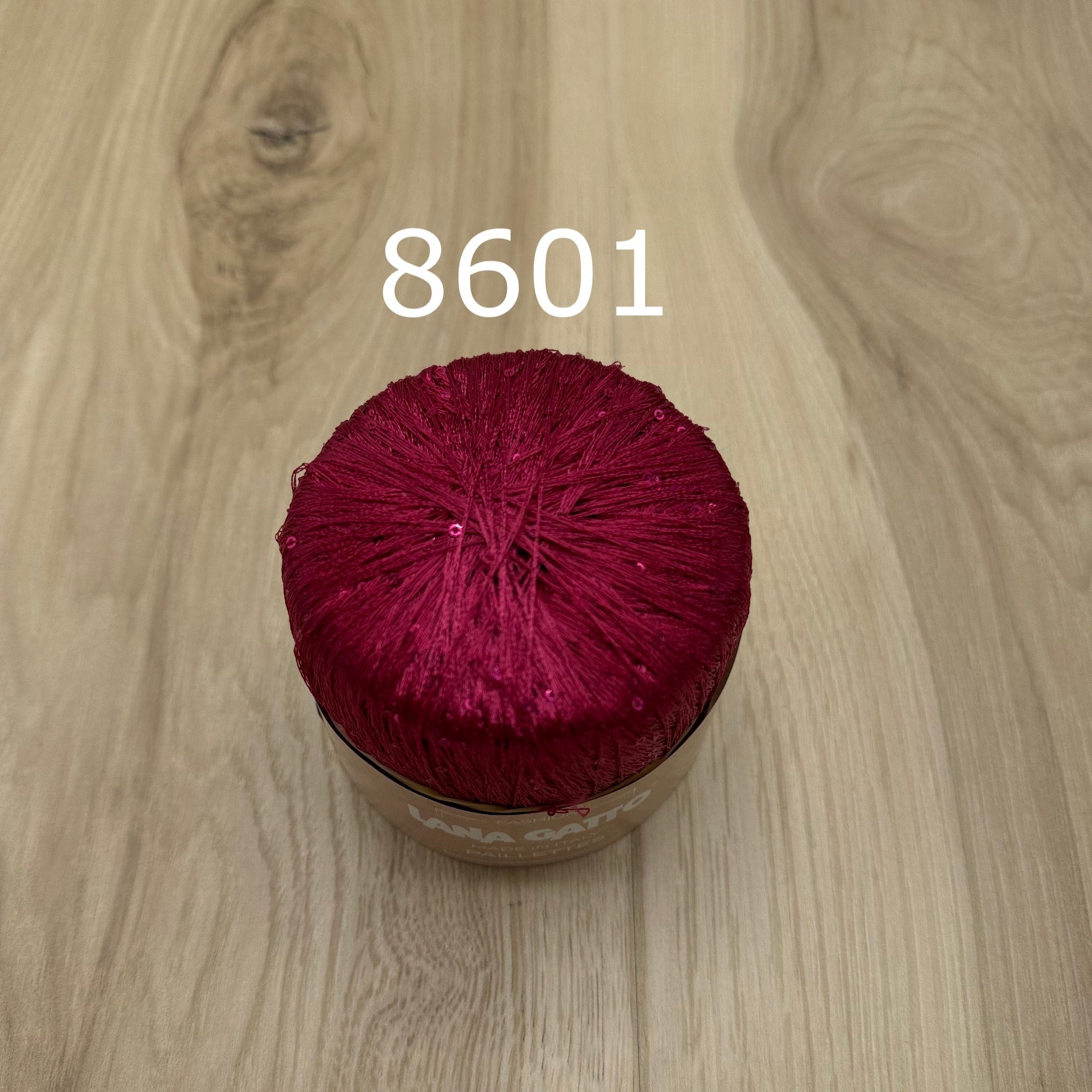 Hot Pink yarn ball with sequins on a wooden surface with the number 8601.