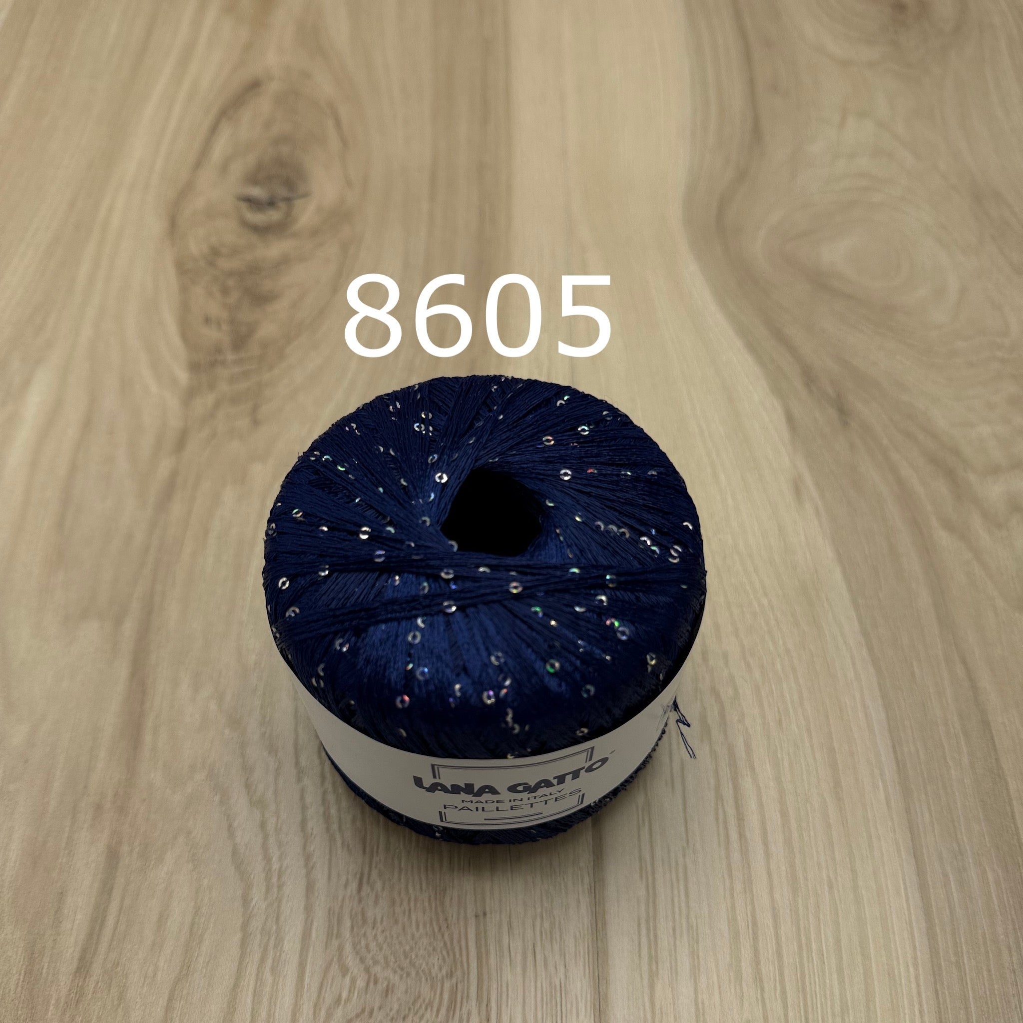 Navy blue ball of yarn with sequins on a wooden surface