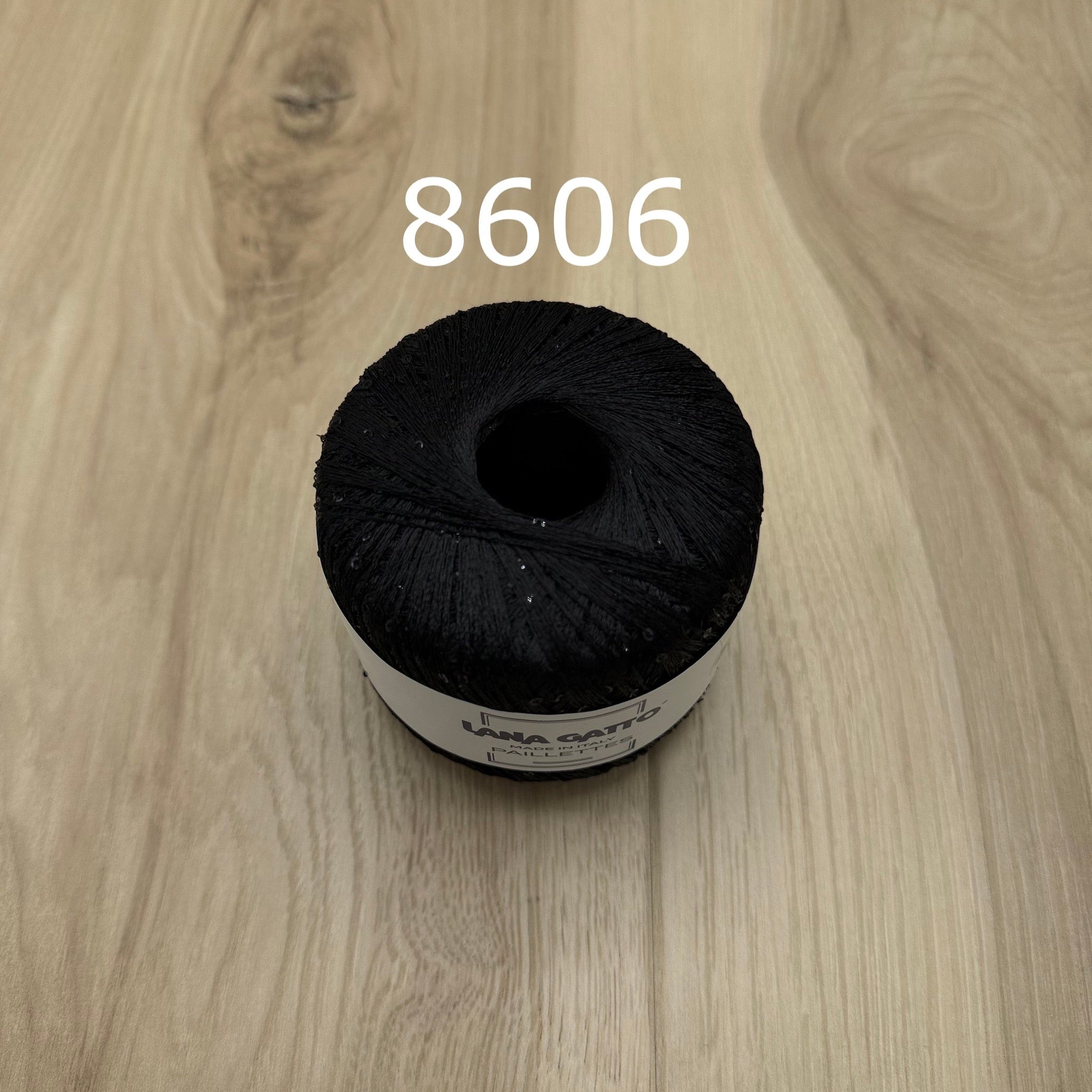 Black yarn ball with sequins on a wooden surface