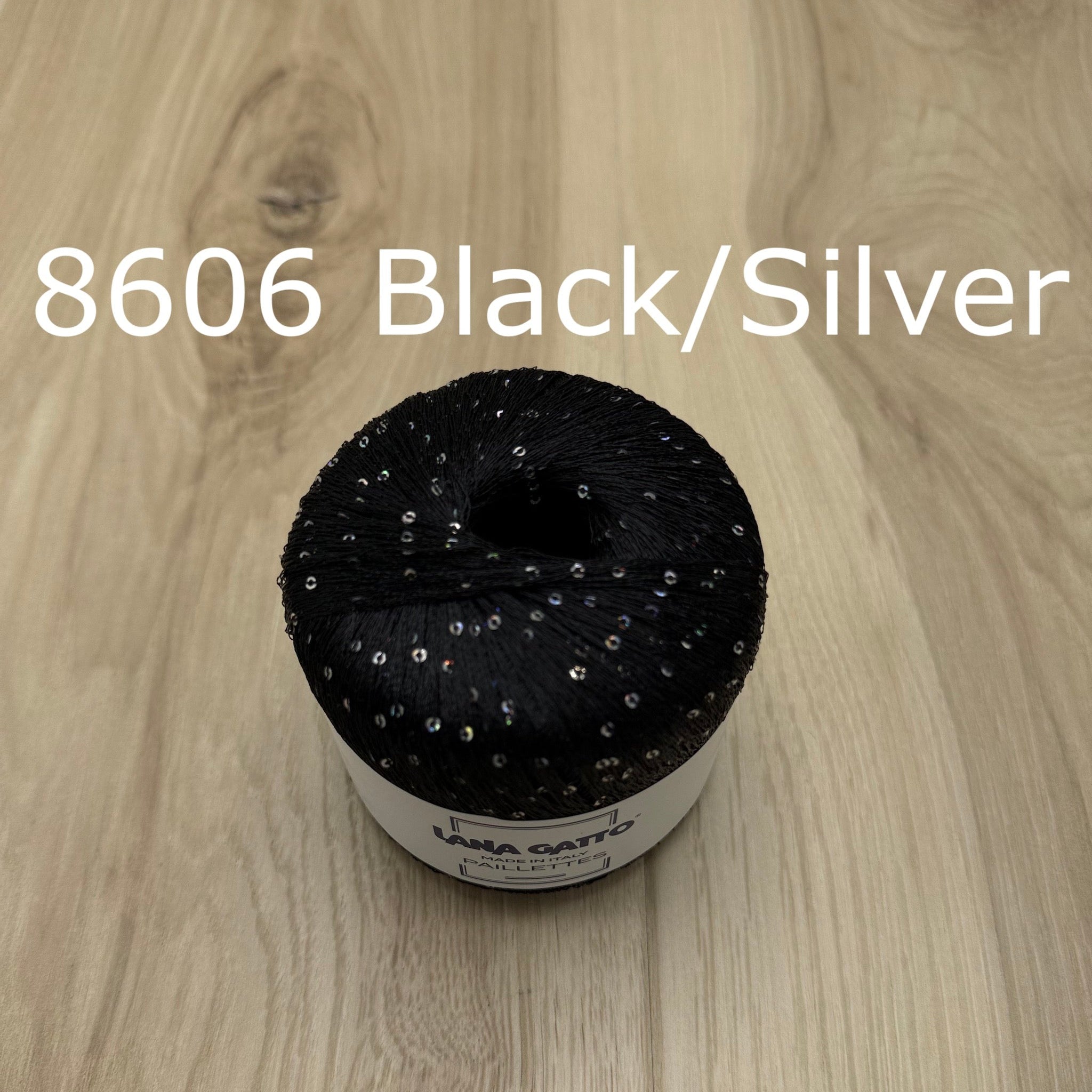 Black/Silver yarn with sequins on a wooden surface 