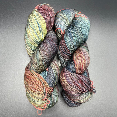 variegated fingering weight wool in shades of moody greens, blues, yellows, and purples