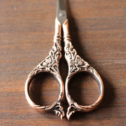 Decorative scissors with ornate handles on a wooden surface
