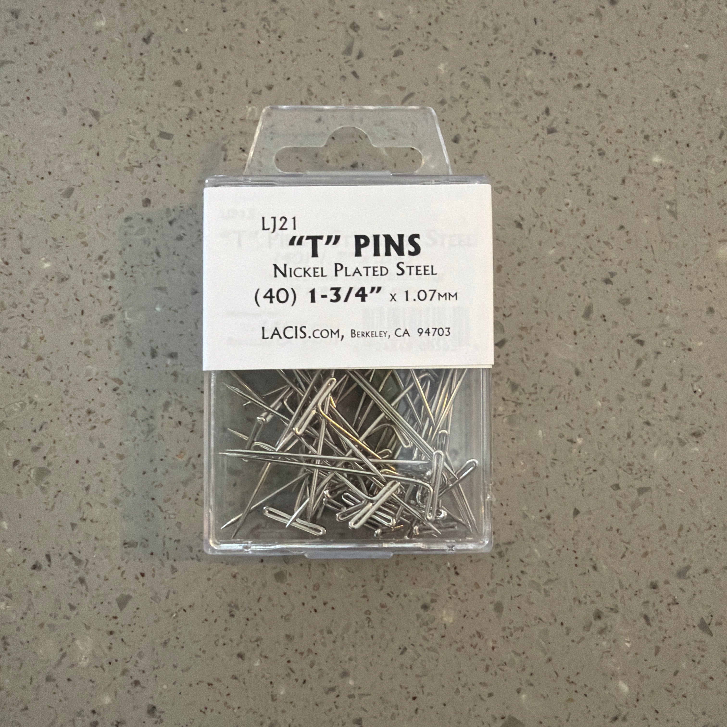 Pack of 'T' pins with a label on a gray surface