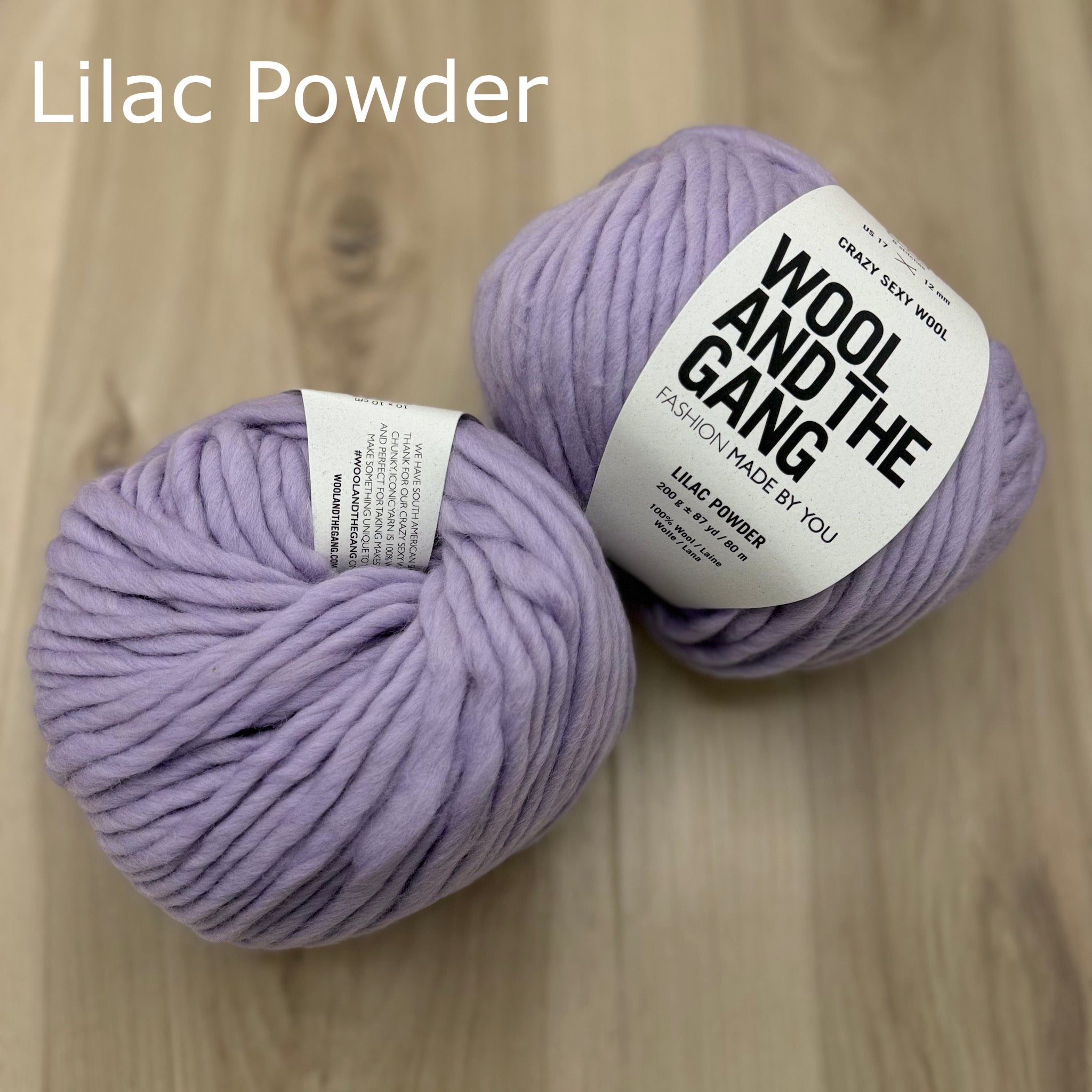 Two balls of super-bulky lilac yarn with 'Wool and the Gang' labels on a wooden surface.