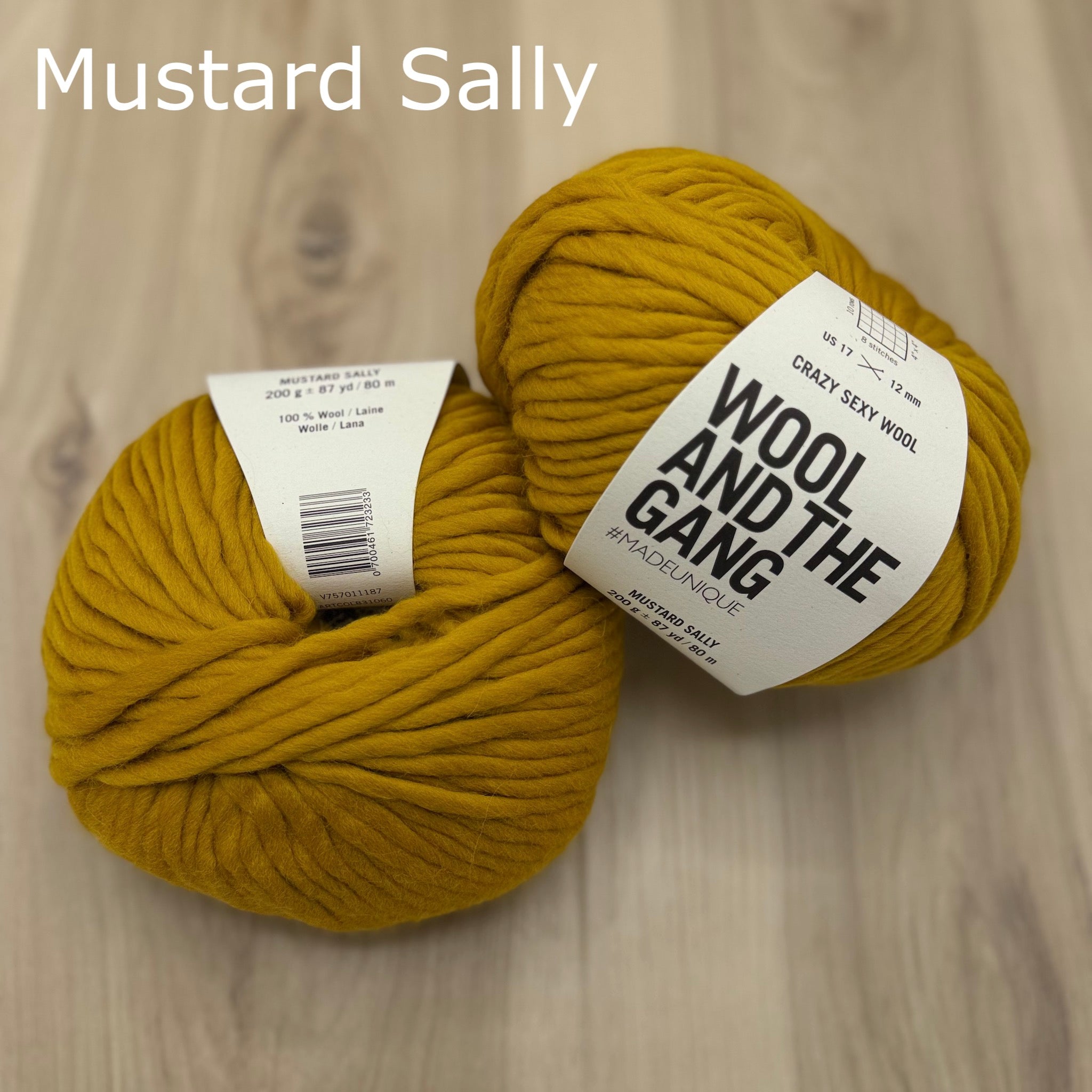 two balls of super-bulky mustard yellow yarn ball with 'Wool and the Gang' label on a wooden surface