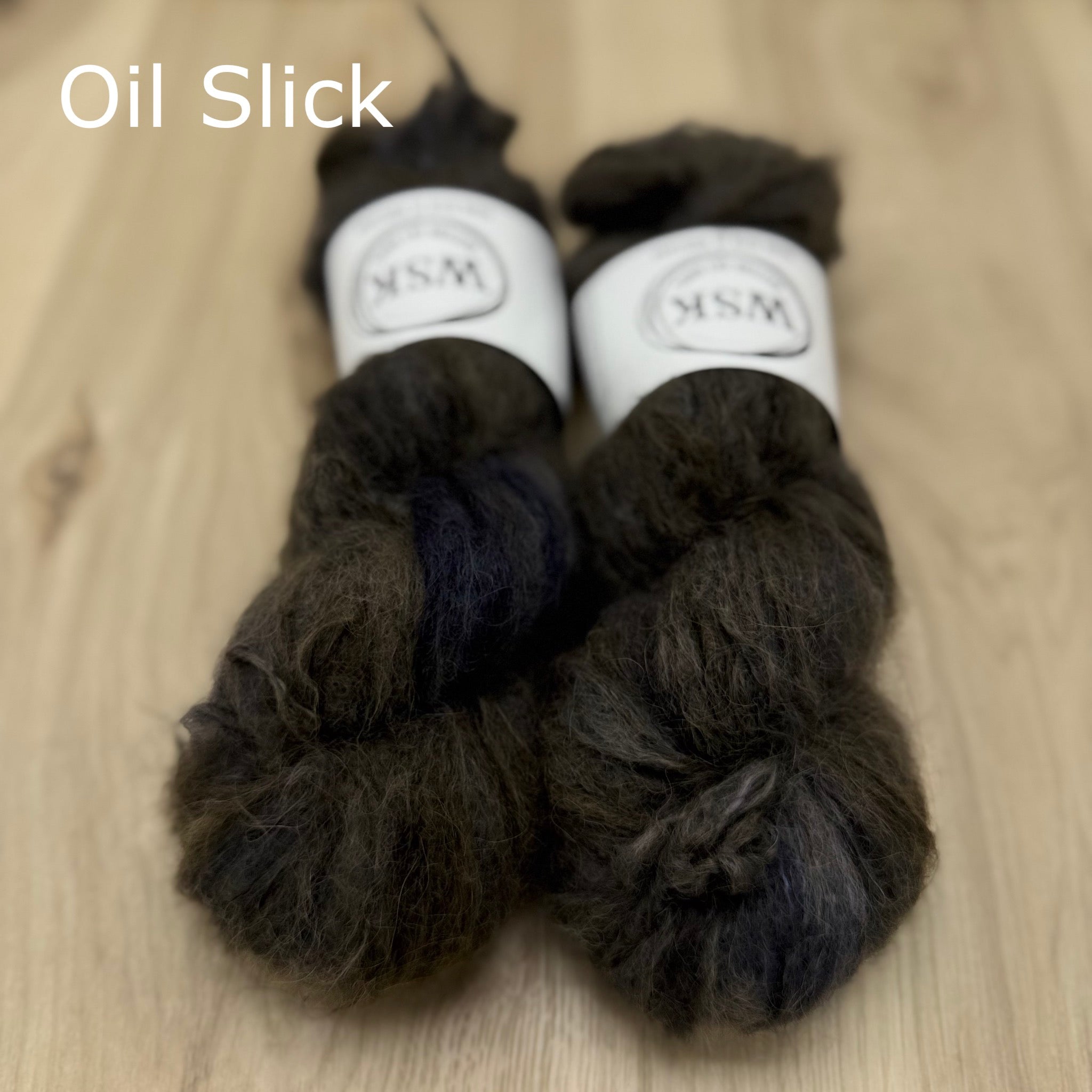 Two skeins of brown and blue fuzzy yarn on a wooden surface