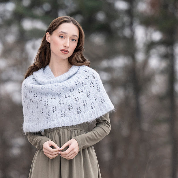 Woman wearing a white lace shawl over a green dress in a forest setting