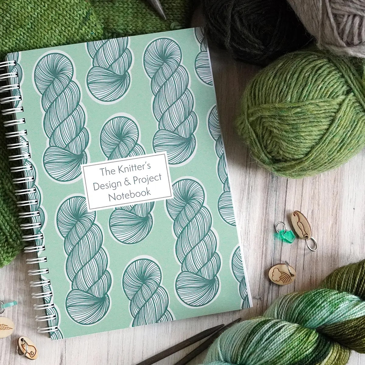 Knitter's Design & Project Notebook with yarn and knitting tools on a wooden surface