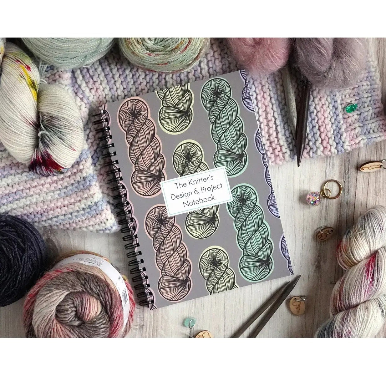 Knitting notebook with yarn and knitting tools on a wooden surface