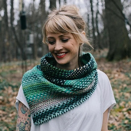 Woman wearing a green patterned shawl in a forest setting