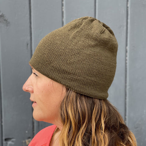 Photo of a person wearing an olive green hat, shown from a side profile view