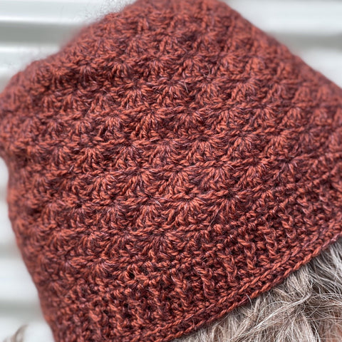 Photo of a russet colored crochet hat, shown from the side